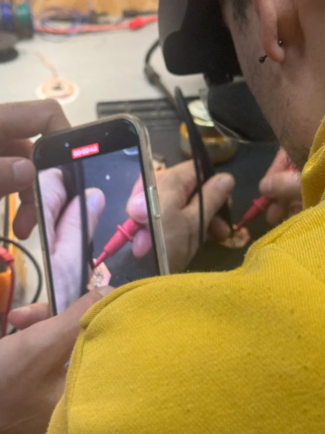 Phone camera magnifying PCB while probing with multimeter