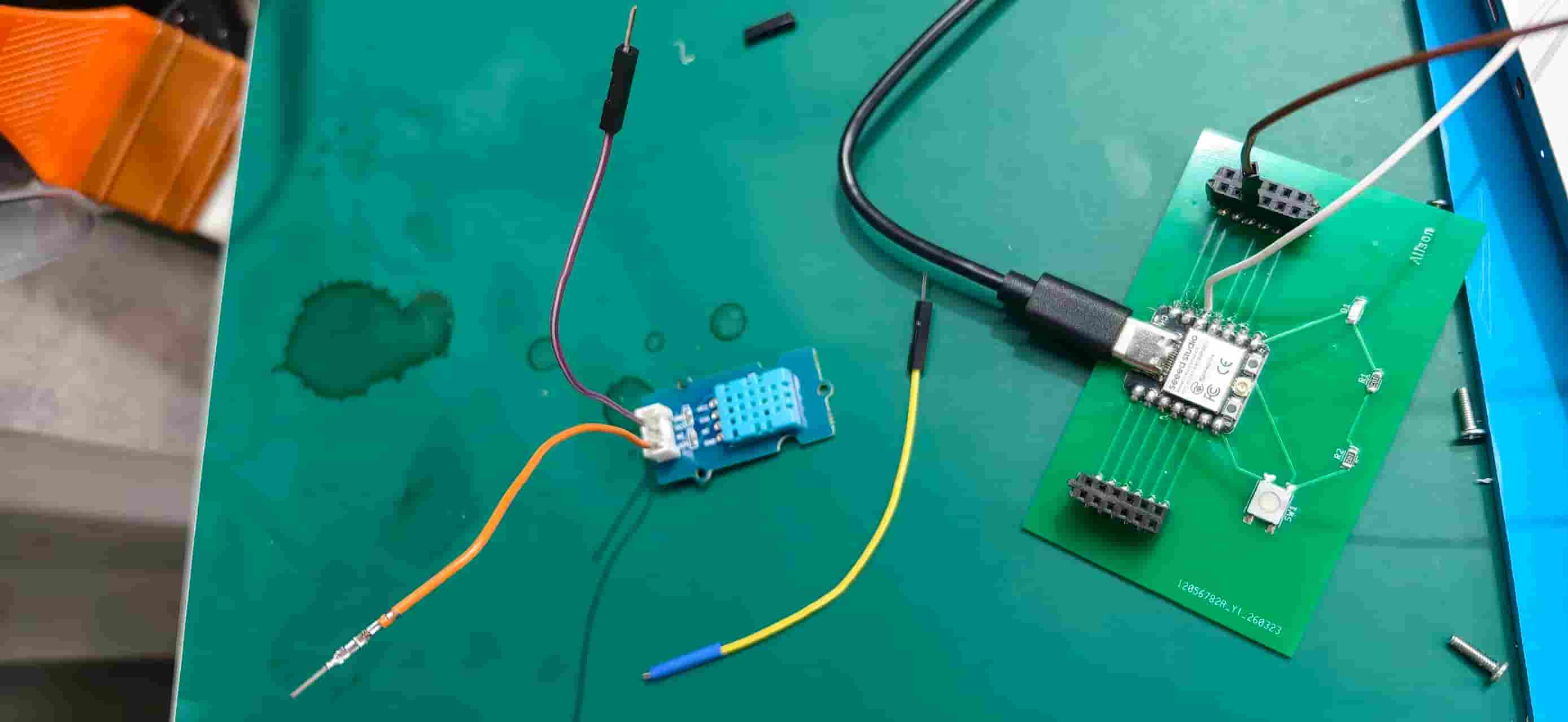 Custom PCB with XIAO and DHT11 wired on a cutting mat