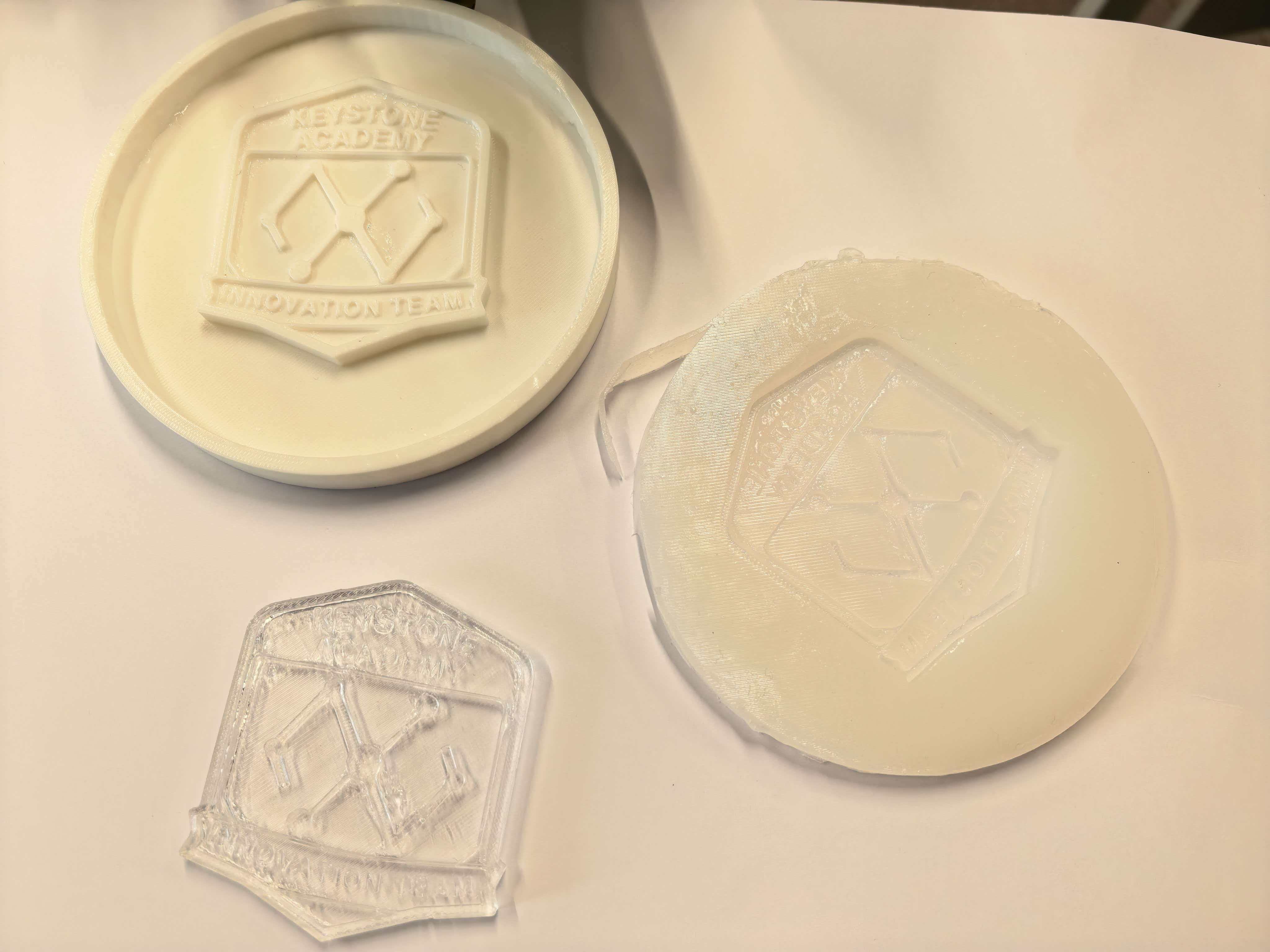 3D-printed master, silicone mold, and clear resin cast arranged together