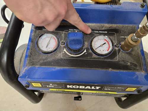 Kobalt compressor gauges with finger pointing to the regulator