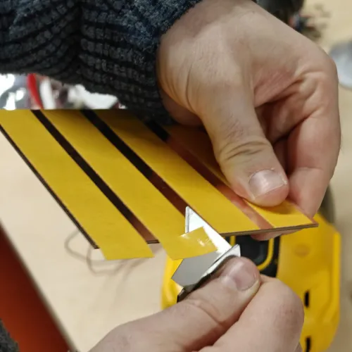 Applying double-sided tape strips to the back of the copper board with a craft knife