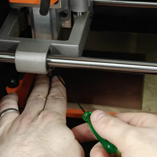 Using an allen key to loosen the collet, letting the end mill drop to the copper surface for Z zeroing