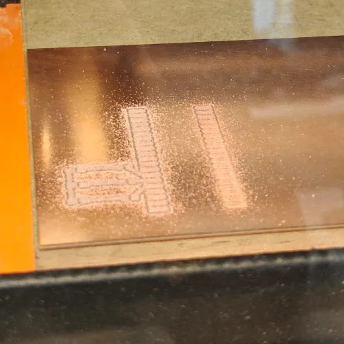 Milled board close-up showing traces under copper dust after first cut