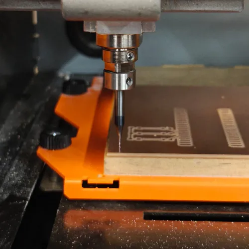 End mill at board edge ready for outline cut, traces visible on the board