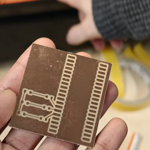 Finished milled PCB held in hand showing clean traces, LED pads on left and Pico SMD pads on right