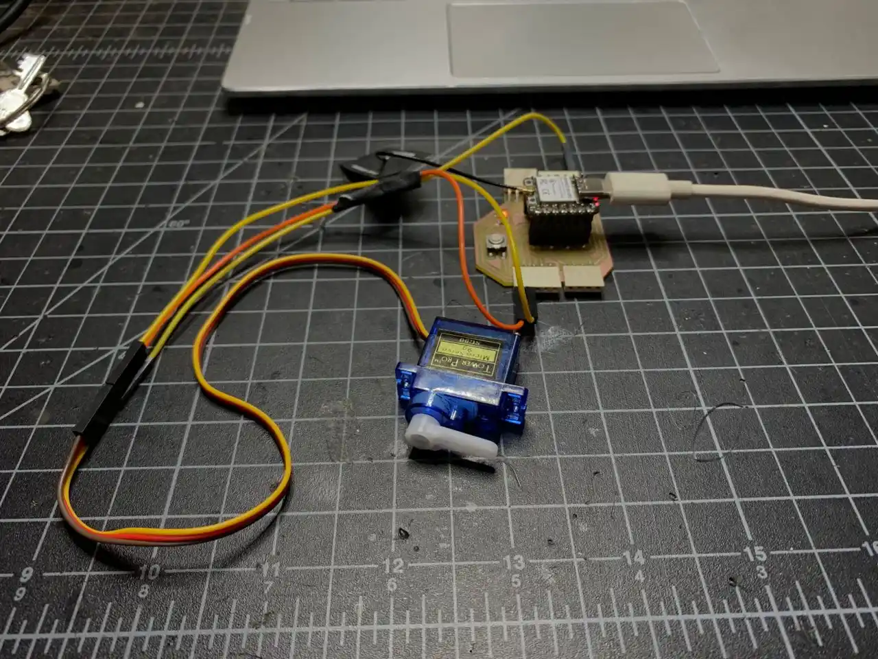 Servo motor and XIAO ESP32-C3 wired up on the cutting mat