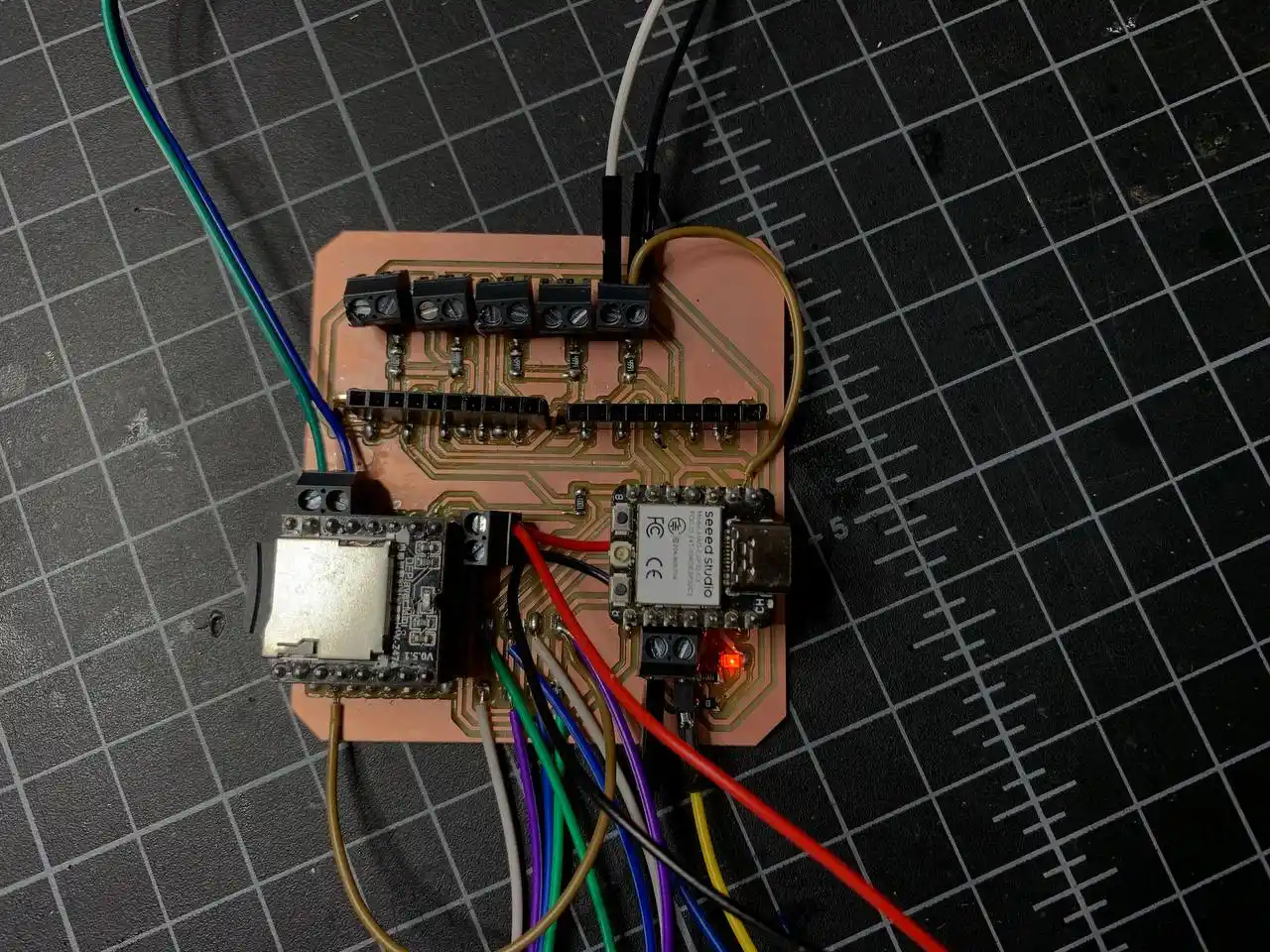 completed PCB with XIAO, DFPlayer, pin headers, screw terminals all soldered and power LED glowing red