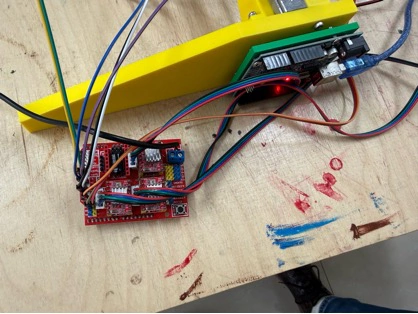 Title: image14.jpeg - Description: Real wiring on the Coloured Plotter — the red CNC shield sitting next to one of the yellow side plates while the motors and endstops are connected.