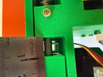 Title: image15.jpeg - Description: Caliper / ruler check on the Coloured Plotter's green frame — verifying the green PLA bracket is at the right offset from the orange reference edge.
