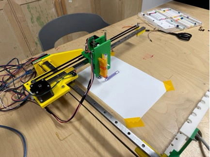Title: image20.jpeg - Description: The green-and-yellow Coloured Plotter set up for its first real drawing — markers lined up on the right, paper taped down, carriage ready to home.