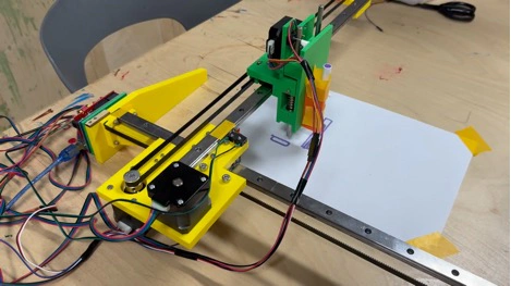 Title: image23.jpeg - Description: Full view of the Coloured Plotter — green printed carriage on steel linear rails, yellow side plates, belts routed for XY motion.