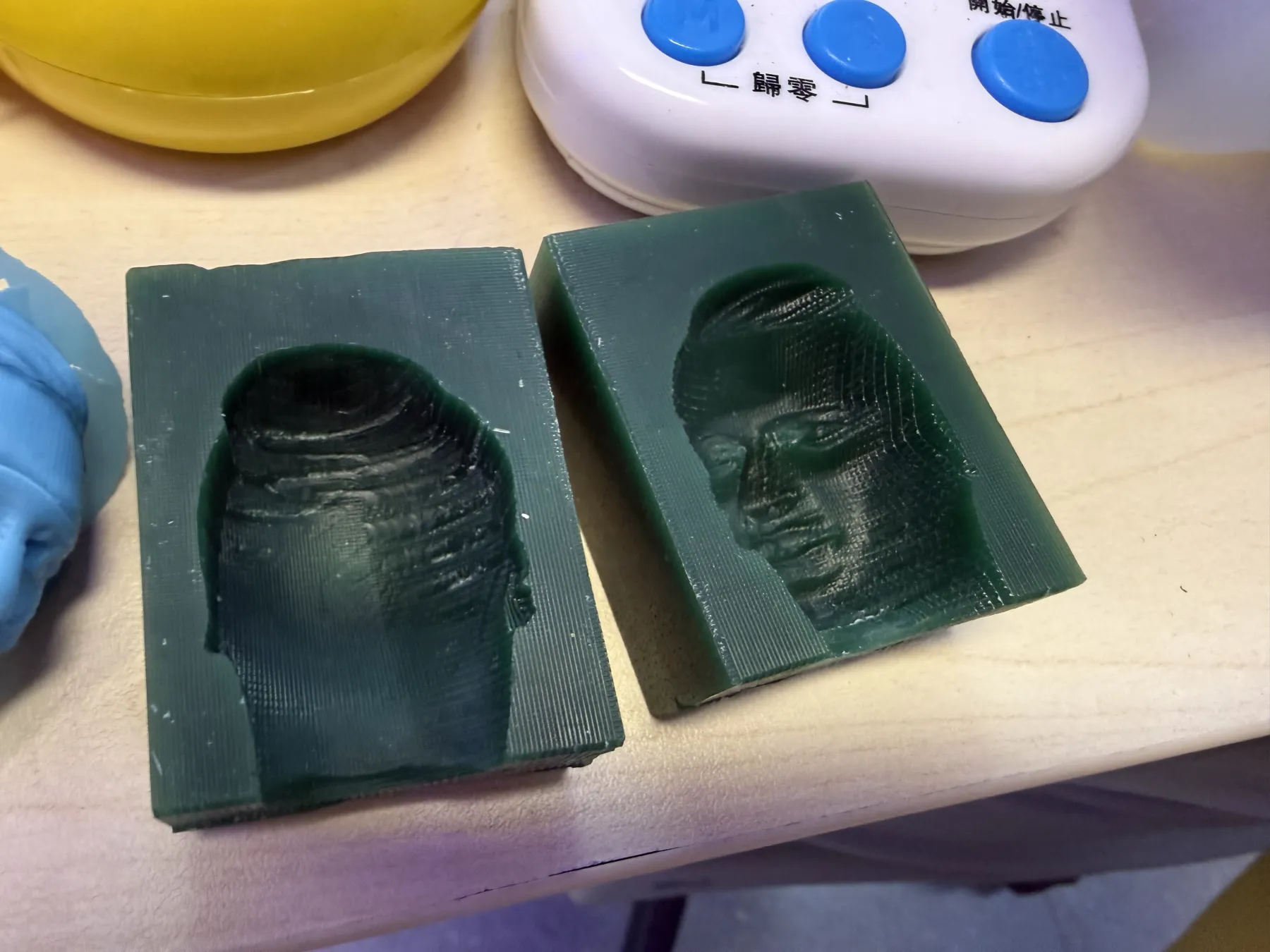 Two finished halves of the milled wax face mould showing the remaining finishing toolpaths