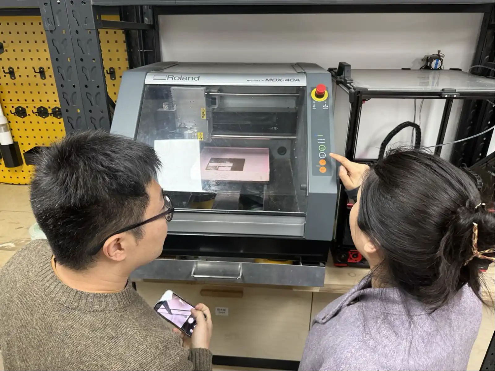 Examining the Roland MDX-40A at the Fab Lab – two people inspecting the machine before the first job