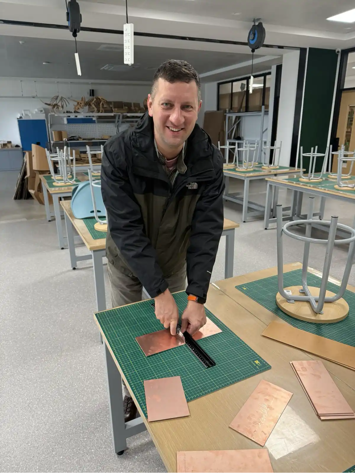Scoring a copper-clad board with a utility knife along a steel ruler on a cutting mat