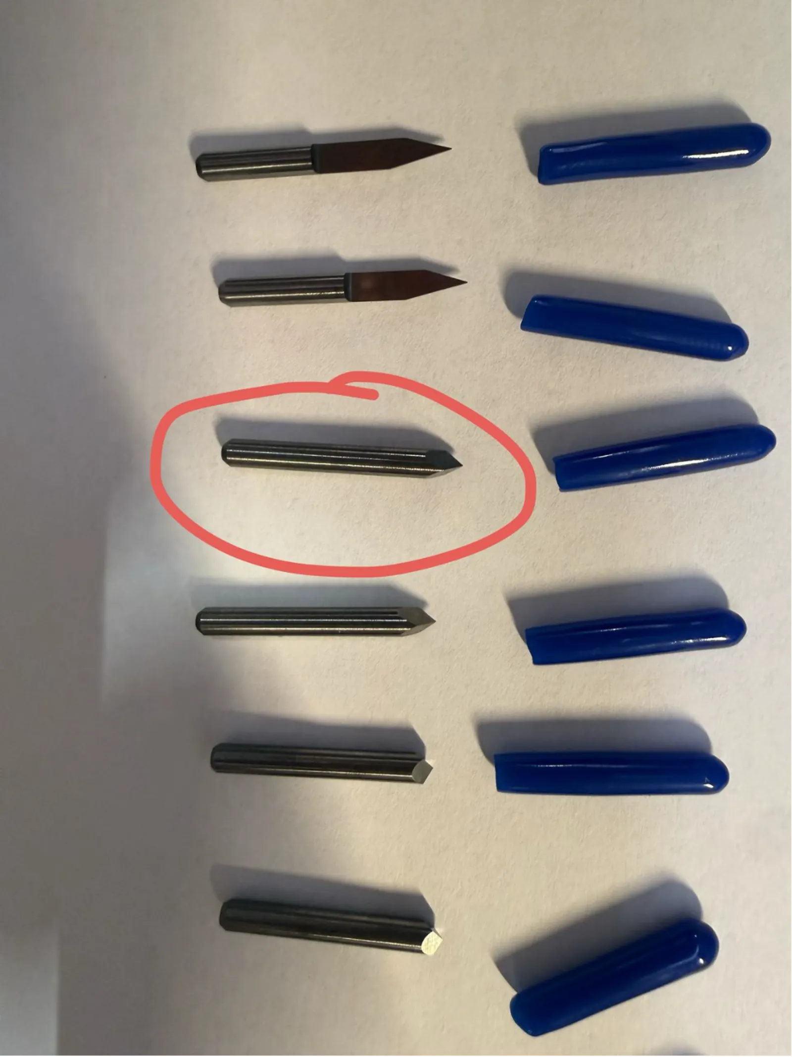 V-bits laid out for selection – the circled bit (highlighted in red) is the chosen engraving bit for this job
