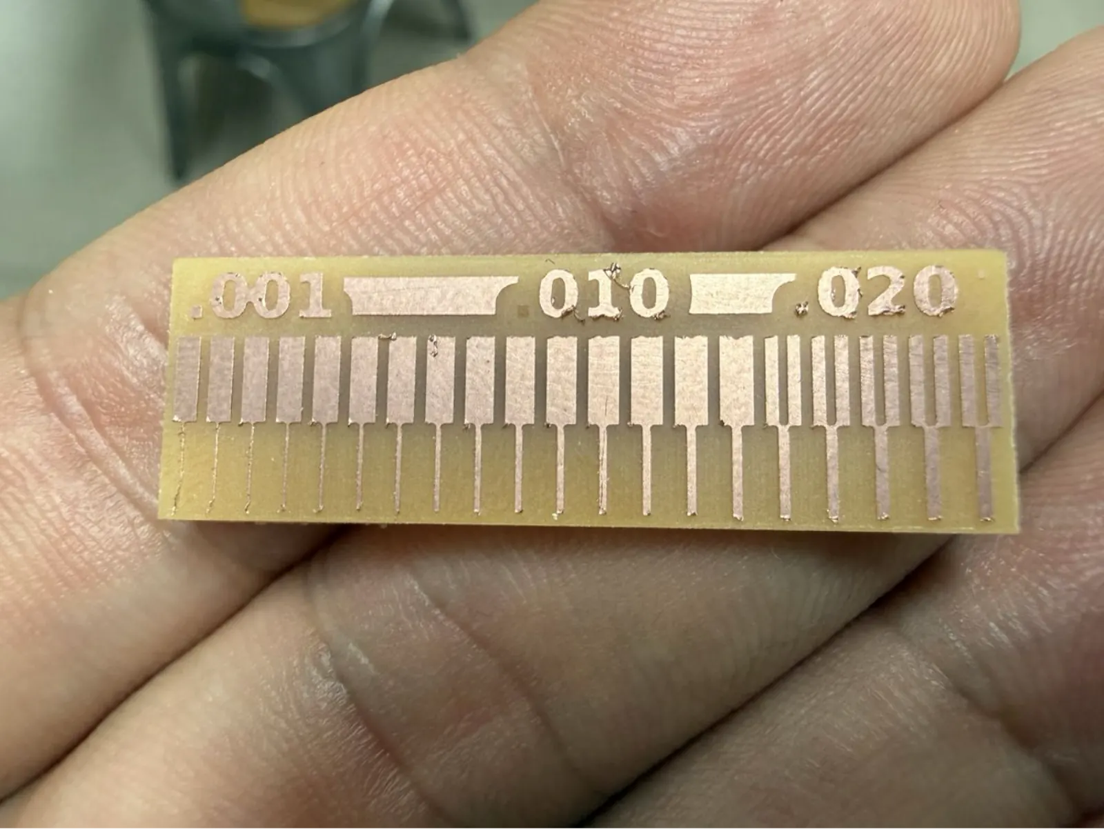 The completed trace width test piece held in hand – fine traces at left, wider traces at right. The 0.010" zone produces reliably clean isolation.