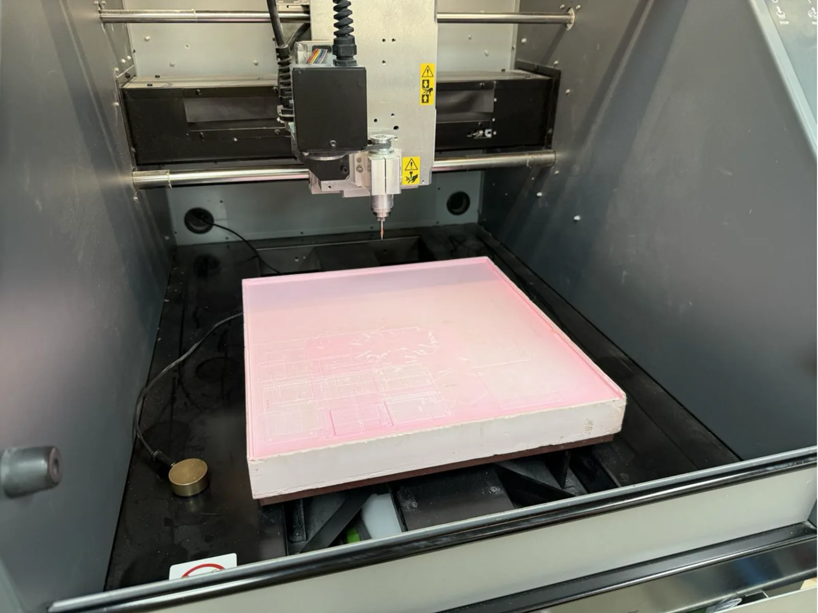 Roland MDX-40A interior with the copper board loaded on the pink foam sacrificial layer – bed levelling marks visible on the foam