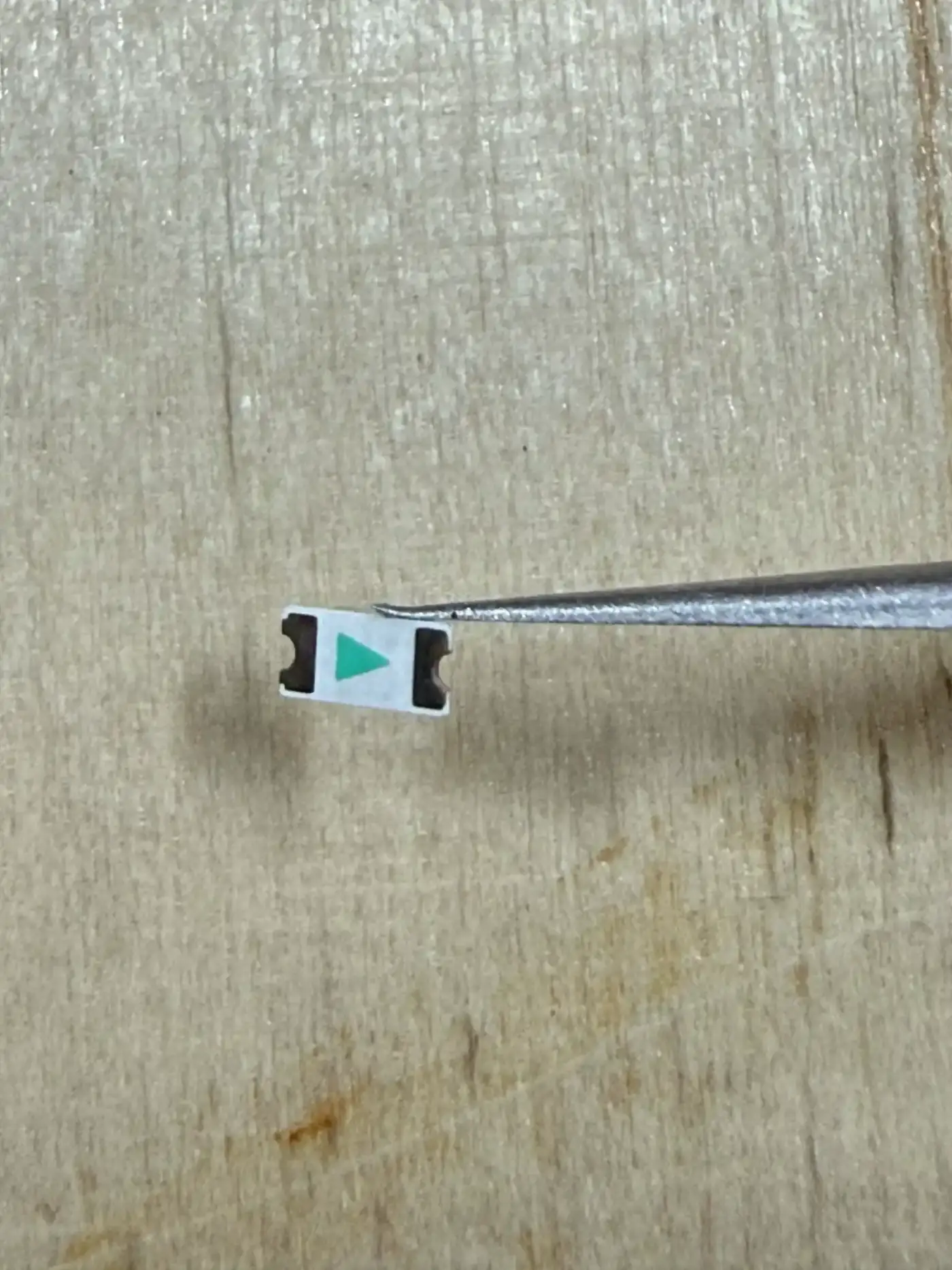 The SMD LED showing its polarity marking – the green arrows indicate the cathode direction for correct orientation
