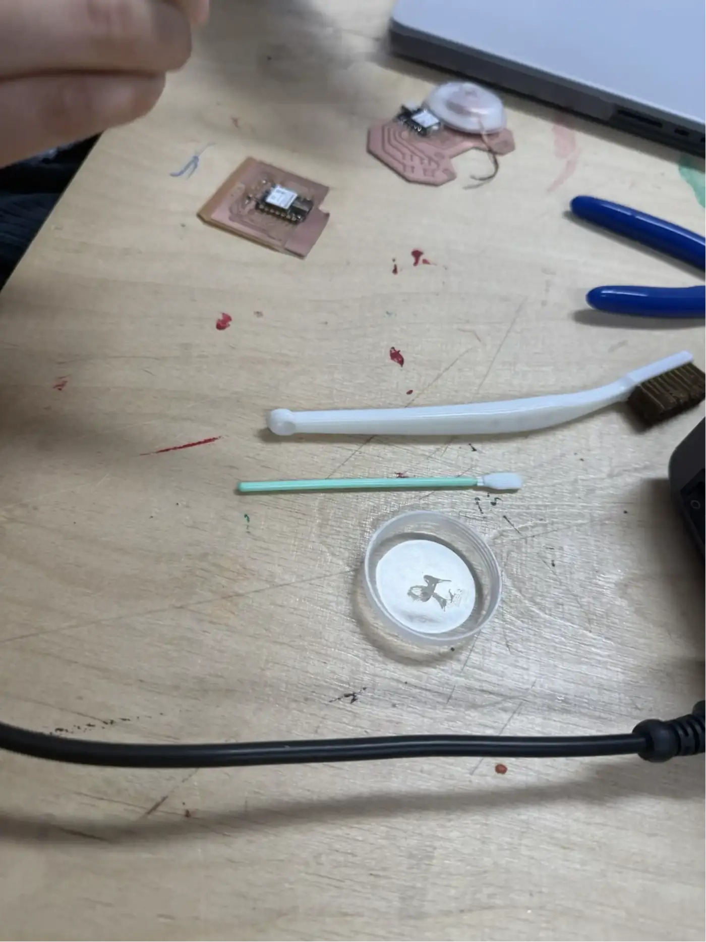 Workbench setup – a partially populated board, cotton swabs for flux application, flux container, and fine-point scraper tools