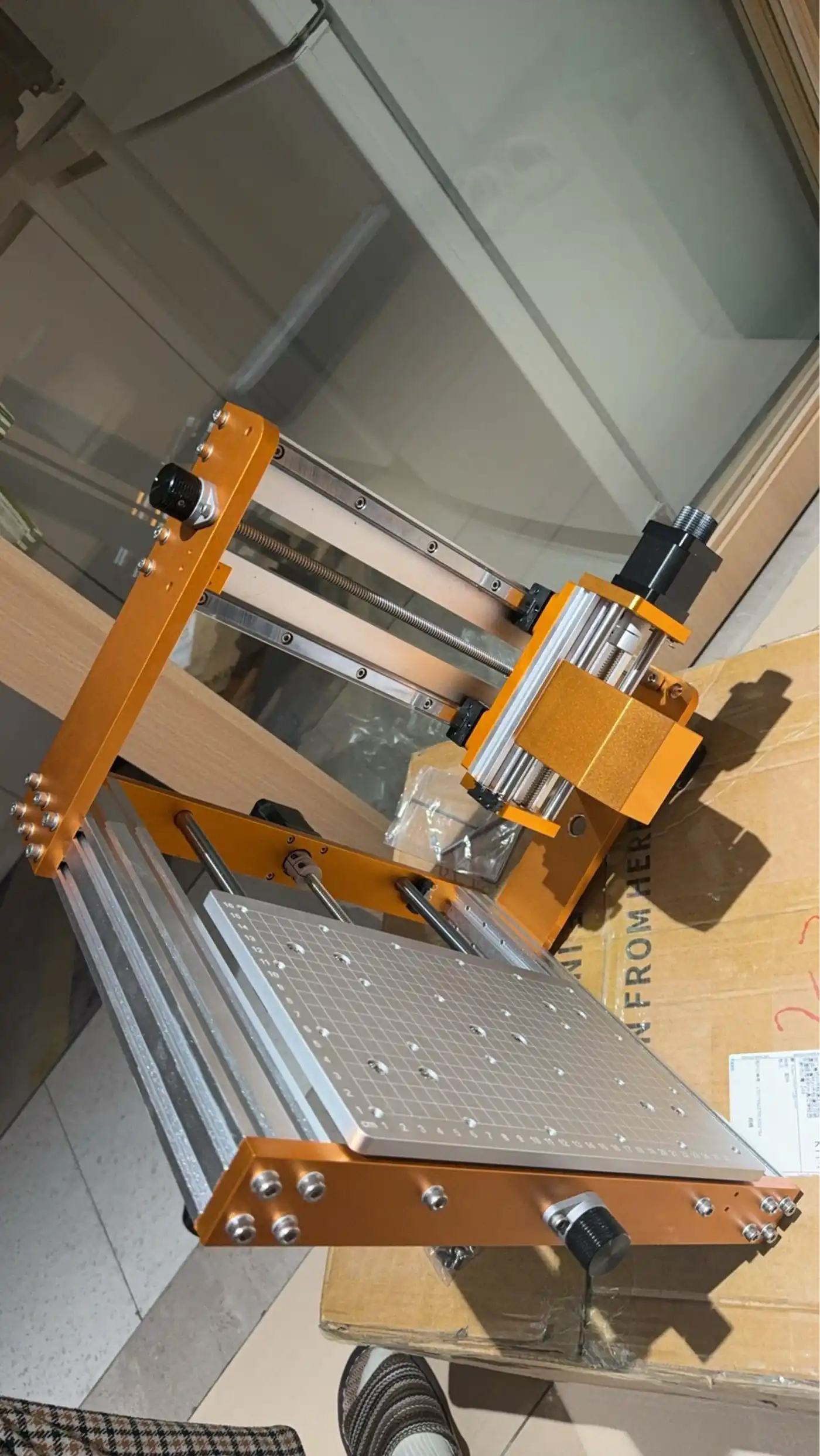 The assembled desktop CNC router – orange anodised aluminium frame, vacuum-hole bed, and spindle mount
