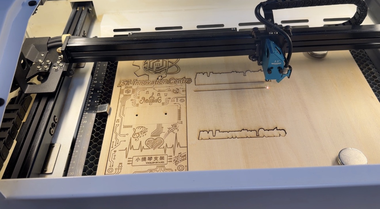 Laser cutter engraving the violin bracket plywood on honeycomb bed