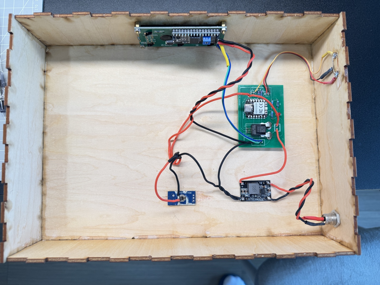 Populated charging dock PCB mounted inside the laser-cut wooden enclosure with wiring