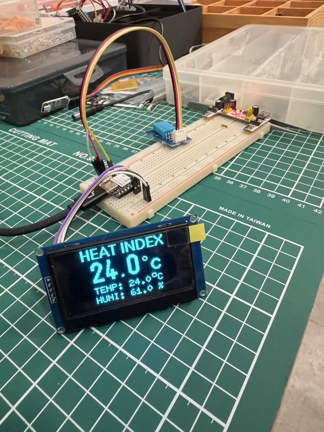 OLED module showing temperature, humidity, and heat-index style readout on breadboard setup