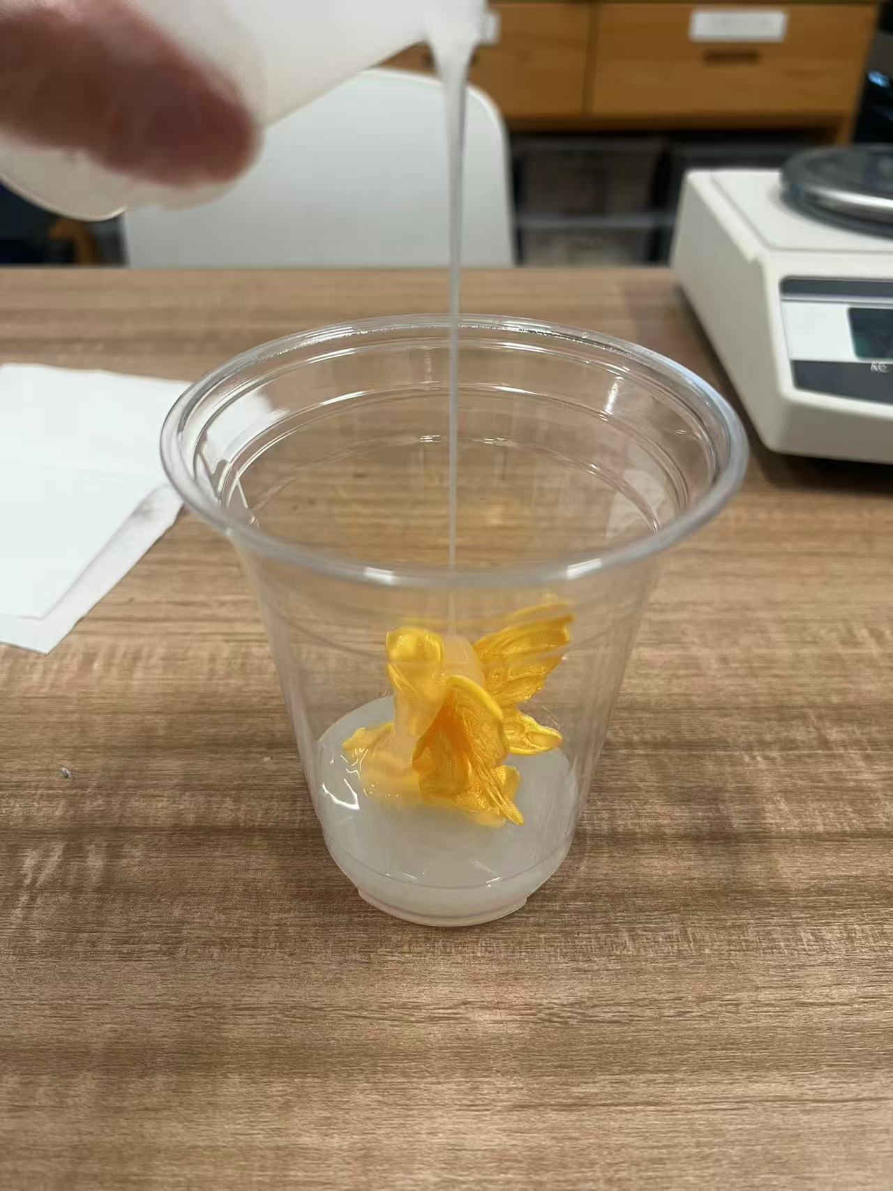 Pouring mixed silicone over the master inside the cup