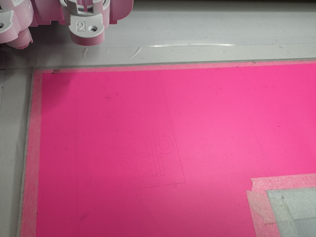 Vinyl cutter cutting the logo on pink vinyl