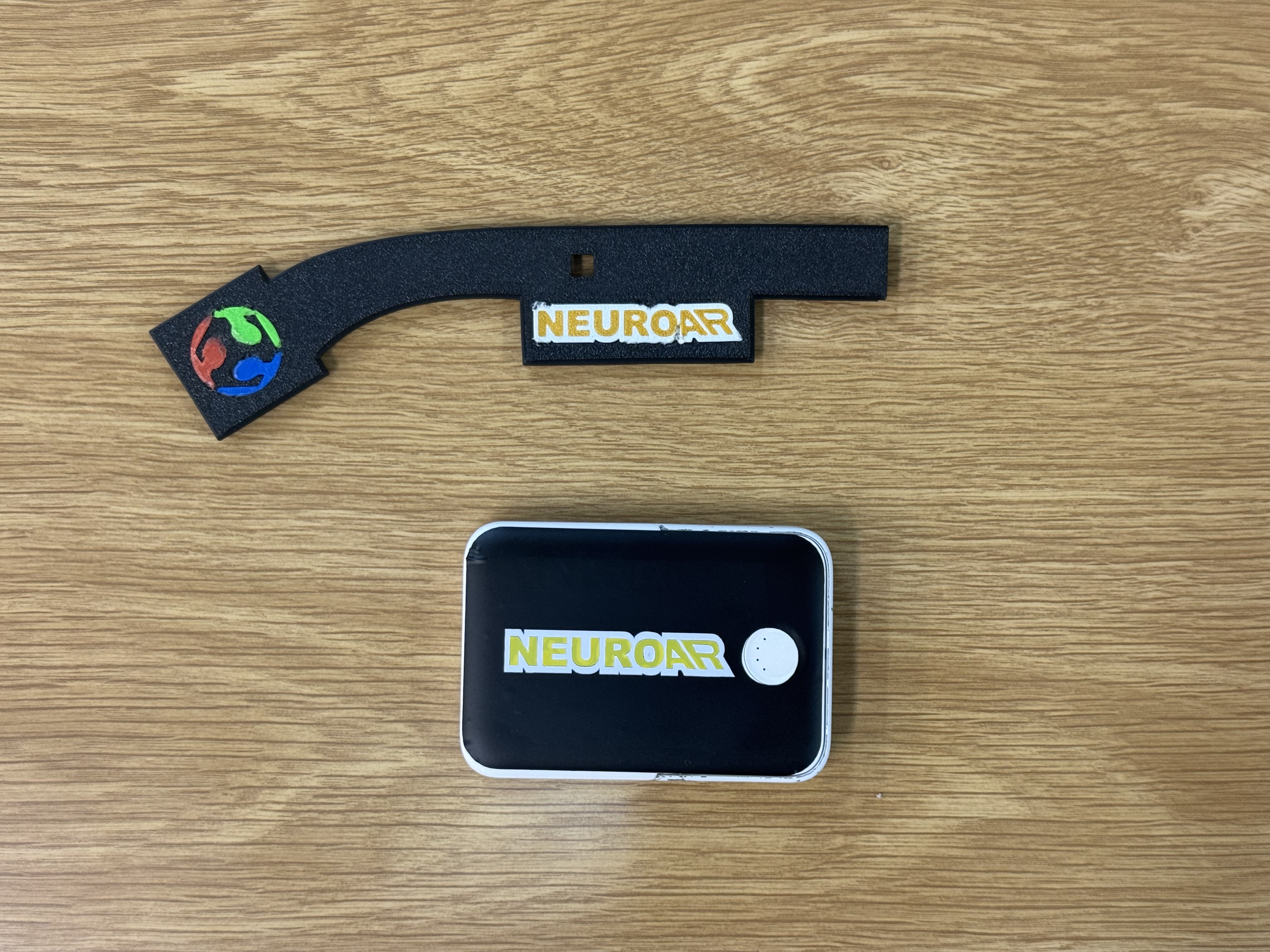 The temple with the NeuroAR wordmark and logo stickers next to the powerbank with its own NeuroAR sticker