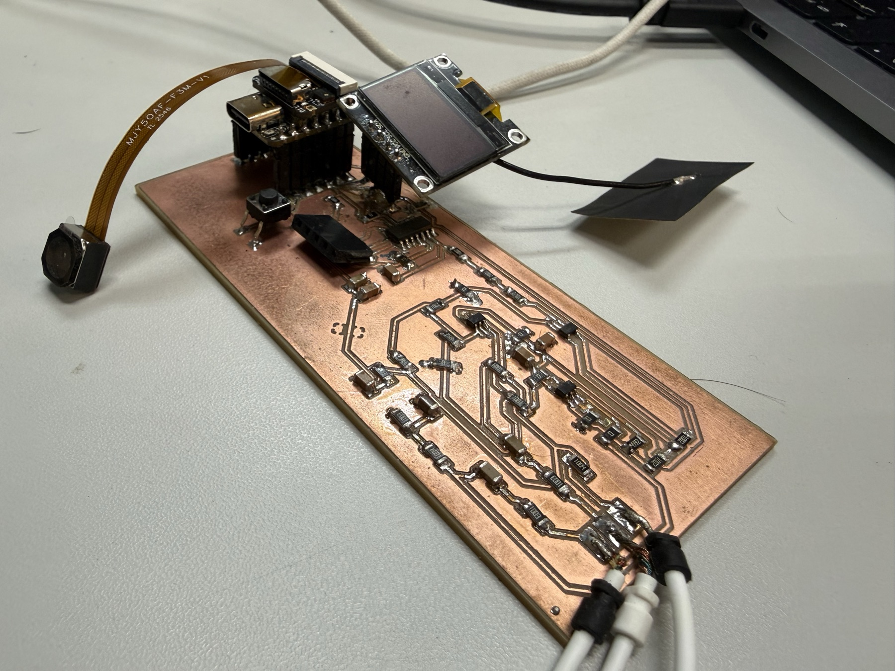 The Spiral 0 EEG board with the XIAO ESP32-S3, SAMD11, OLED, camera module, and electrode leads