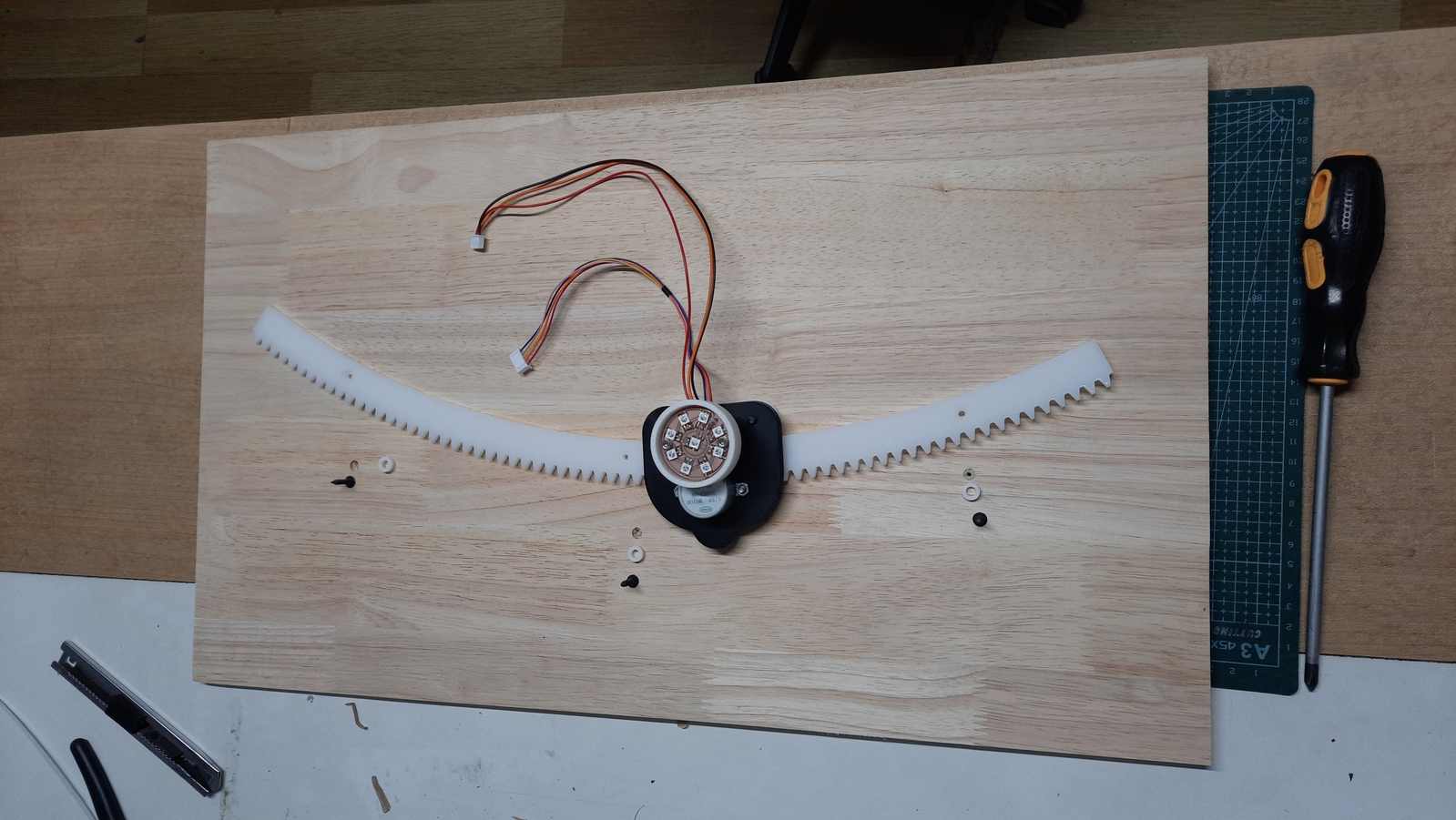 The mounting locations for the gear assembly were defined during the CAM process to ensure accurate alignment. The assembly sequence consisted of the back panel, spacer, acrylic gear, and a 3/4 inch drywall screw with a flush finish.