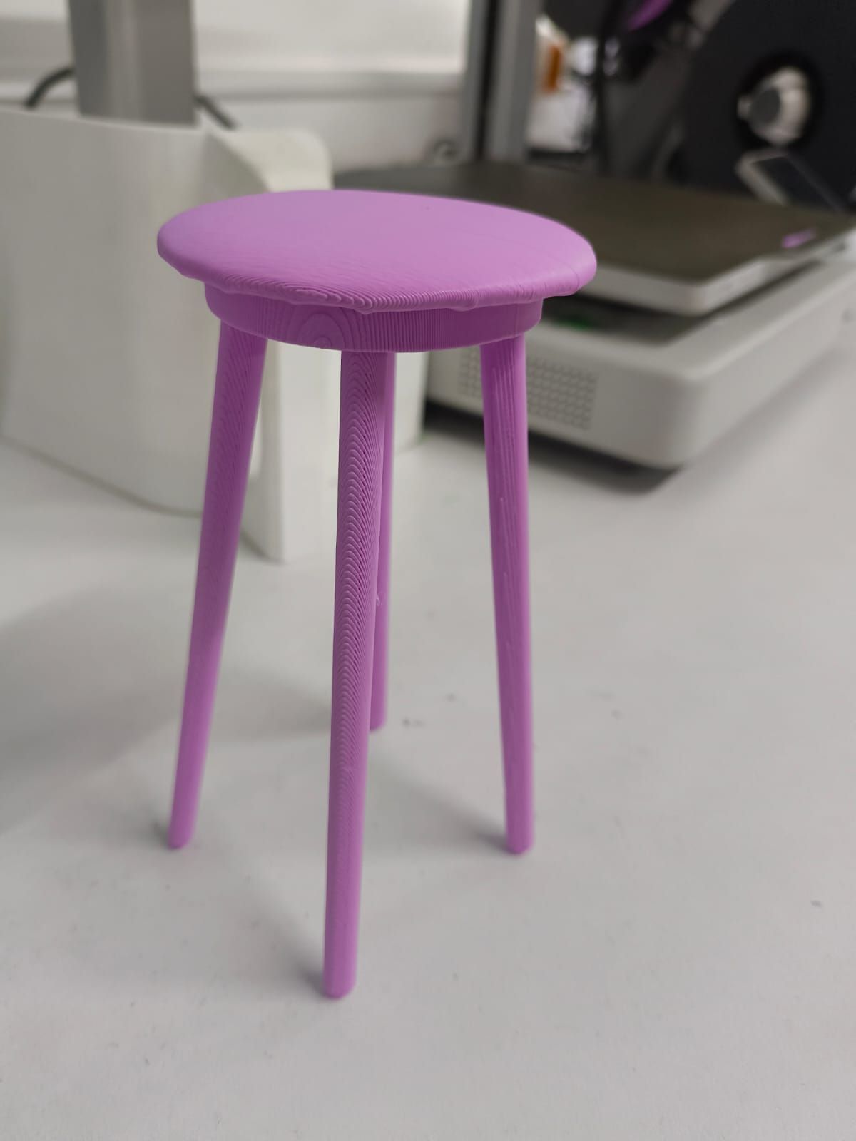 Final 3D printed stool after support removal — clean three-legged miniature stool in lavender PLA