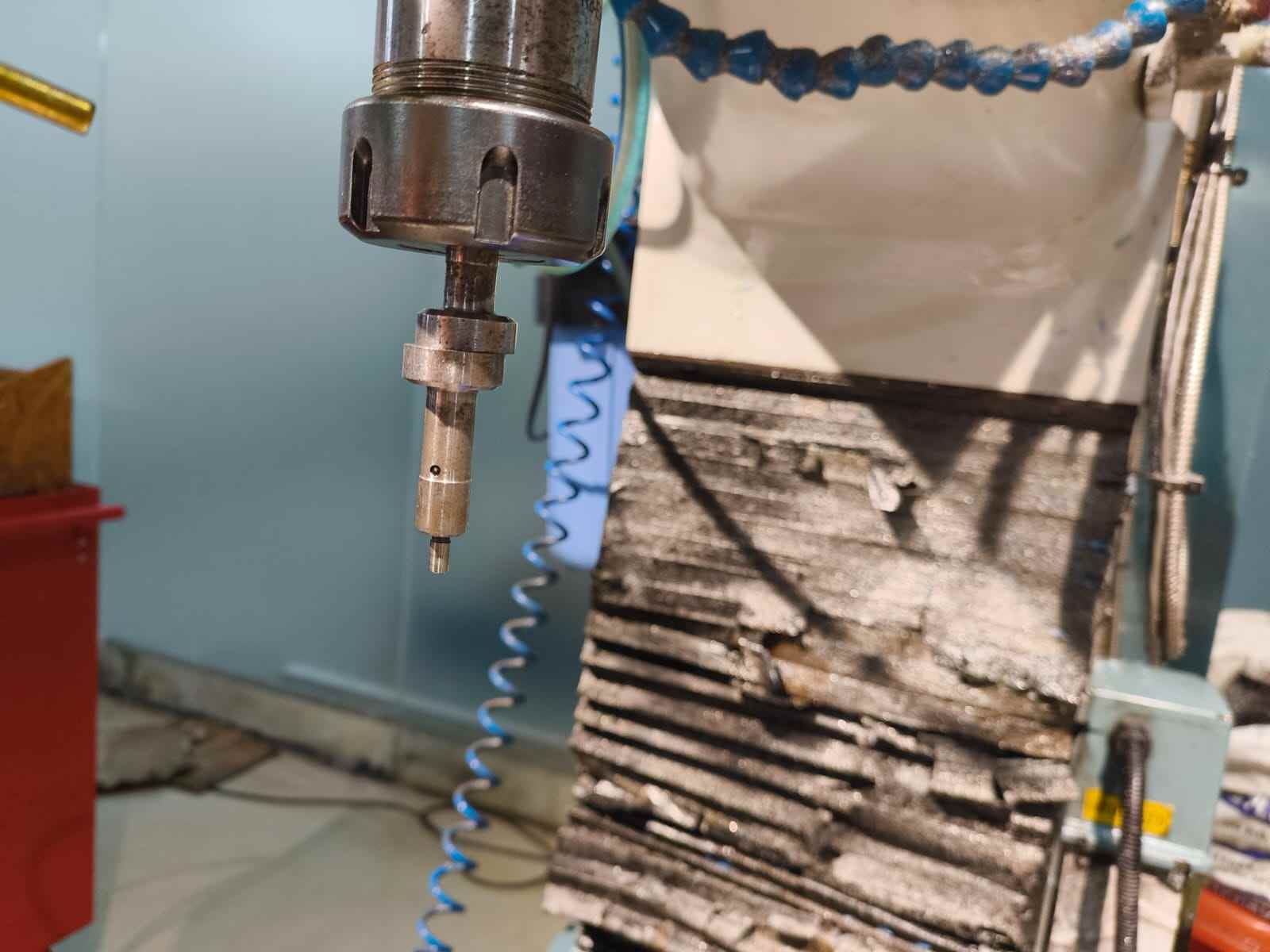 Close-up of the CNC spindle with a small diameter end mill loaded in the collet, positioned near the machine column