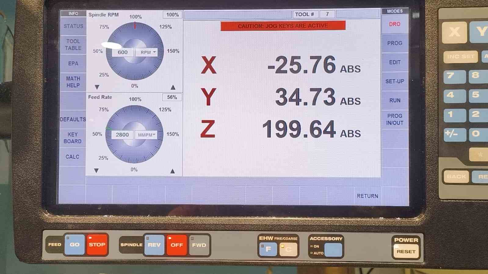 CNC controller DRO screen showing Tool #7, spindle speed 600 RPM, feed rate 2800 MMPM at 56% override, X -25.76 Y 34.73 Z 199.64 ABS, jog keys active warning