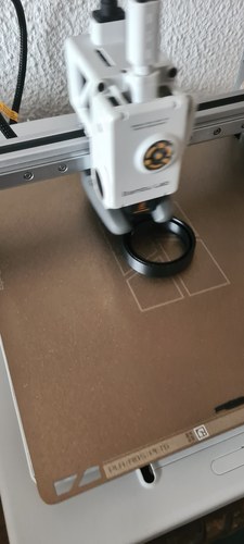 Bambu Lab A1 printer mid-print, toolhead over the textured PEI plate, laying down a PETG part.