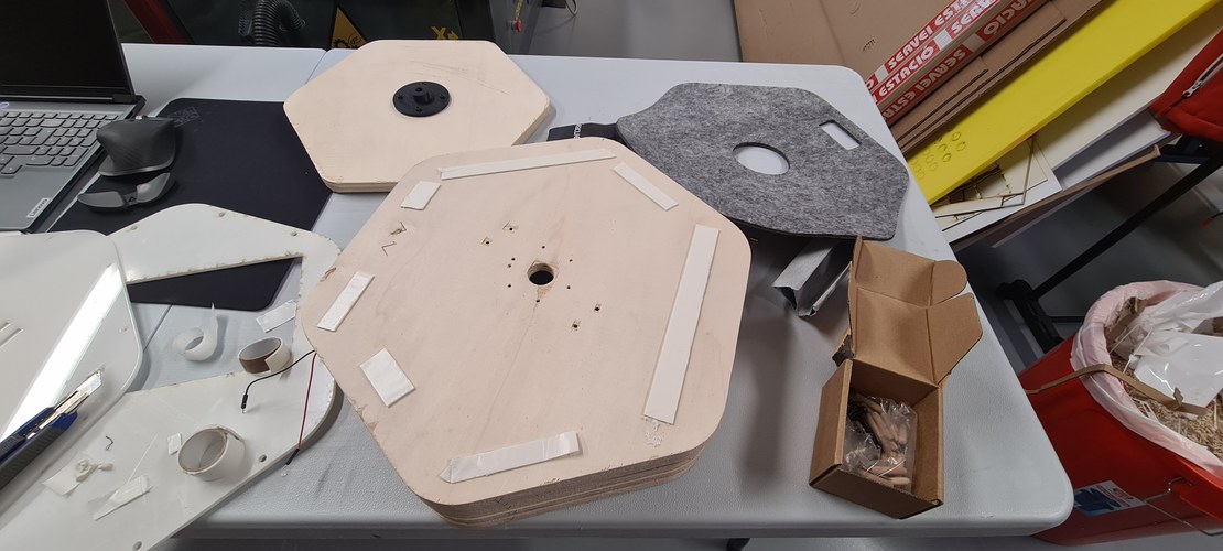 The base parts laid out: the underside with double-sided tape and the felt cut-out, and the motor mount in place.