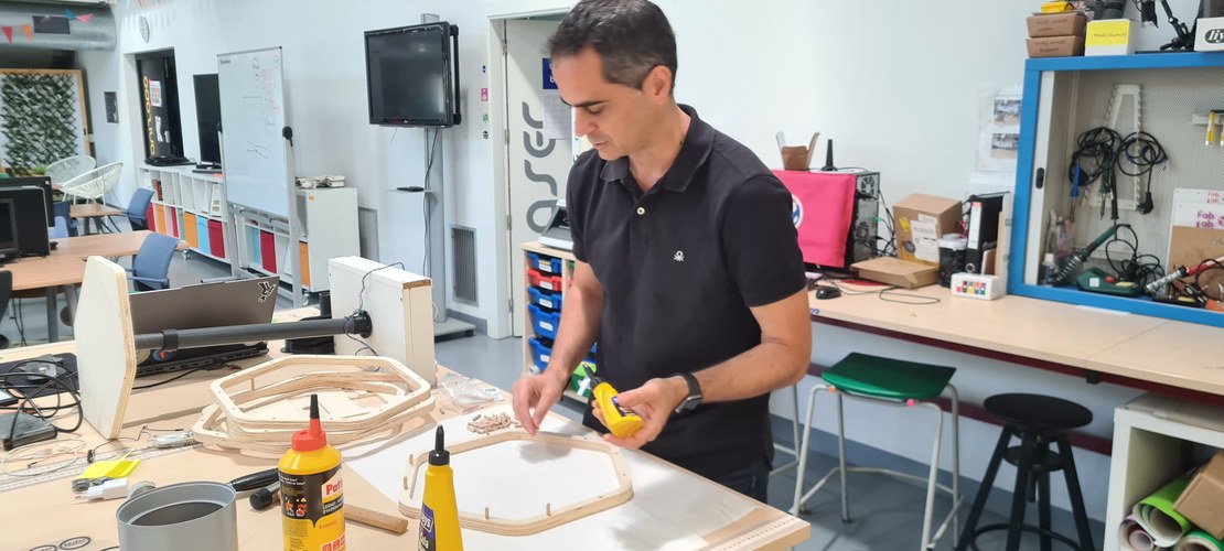 Applying wood glue to dowels at the lab table, the ring frames and a bottle of carpenter's glue in front.