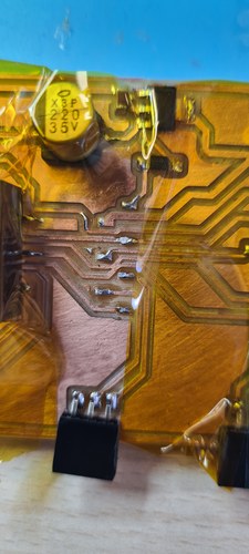 The milled board with amber Kapton tape masking the components around the XIAO socket area during heat-gun desoldering, copper traces and a capacitor marked X3P 220 35V visible.