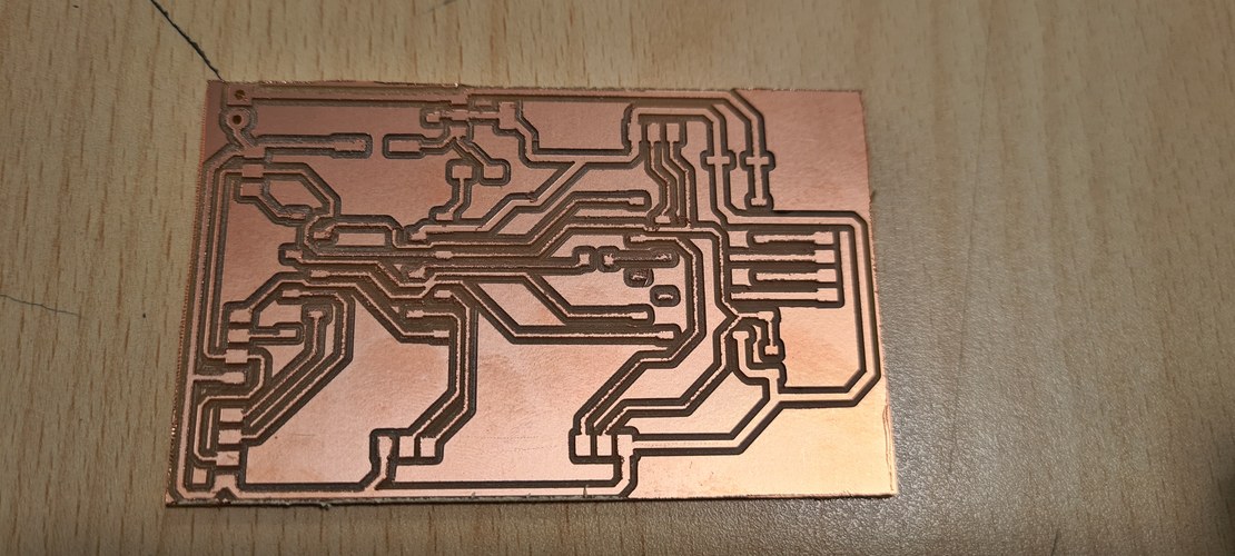 The milled single-sided PCB on the desk, copper traces isolated against the FR1 substrate, before any components are soldered.