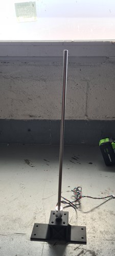 The printed motor mount on its base, with the motor coupled and a long T8 lead screw standing vertically from the flexible coupling.