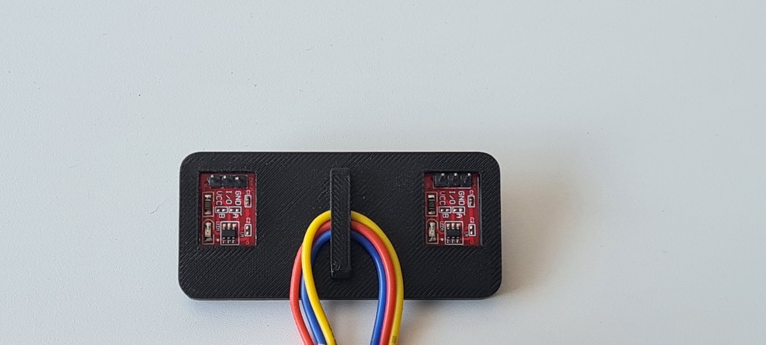 A black 3D-printed panel holding two red TTP223 capacitive touch boards, with red, yellow and blue wires.