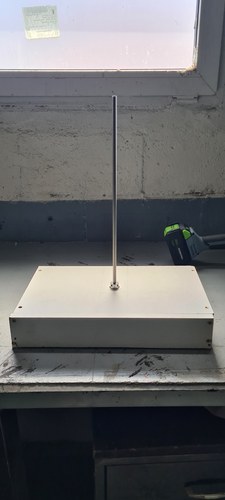 The finished plywood base, painted, with the drive mounted at its centre and the lead screw standing up from it by a window.