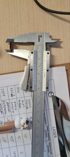 Digital caliper measuring a cut cardboard piece to check the kerf.