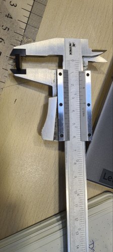Digital caliper measuring the width of a cut cardboard piece.