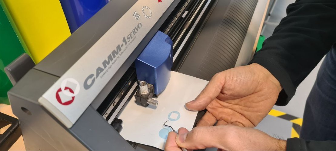 Removing the excess white vinyl around the cut design.