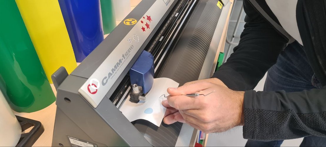 Peeling the finished white sticker off its backing at the machine.