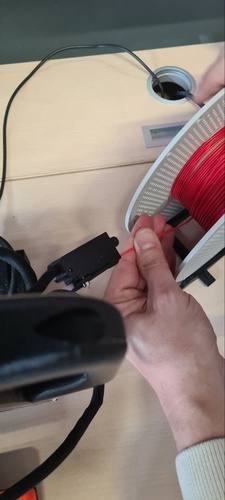 Feeding red PLA filament into the Prusa Mini sensor.