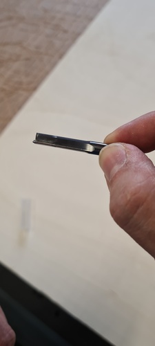 Close-up of the cutting end of the 6 mm end mill held between two fingers, showing the single straight flute.