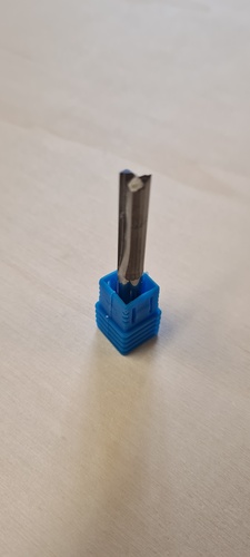 A 6 mm single-flute end mill stored vertically in its blue plastic protective holder.